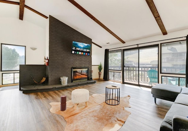 living room with beamed ceiling, high vaulted ceiling, wood finished floors, and a fireplace