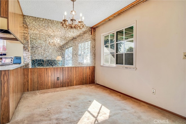 interior space with a notable chandelier, wood walls, and a textured ceiling