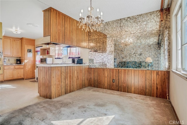 kitchen with light brown cabinetry, light colored carpet, light countertops, and an inviting chandelier