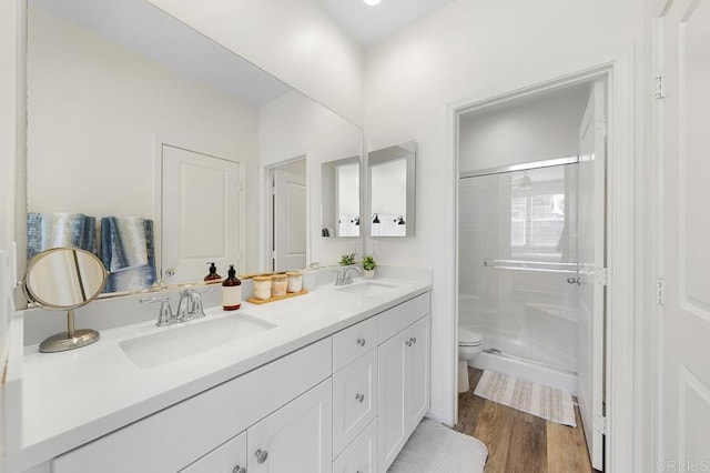 full bath featuring wood finished floors, a stall shower, toilet, and a sink