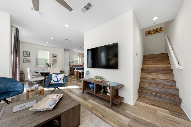 living area with visible vents, recessed lighting, light wood finished floors, ceiling fan, and stairs