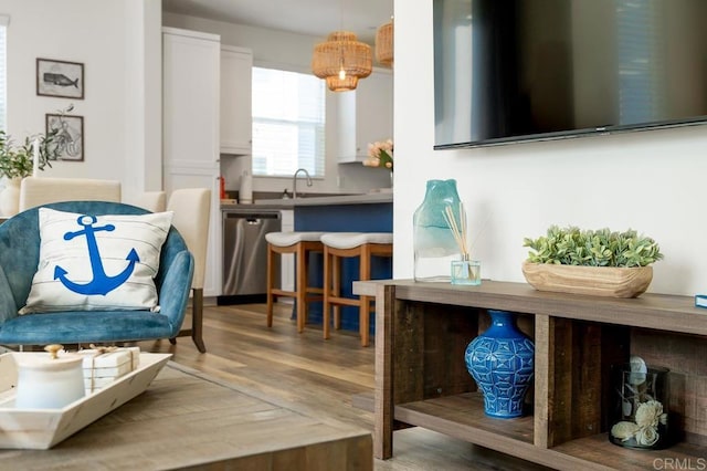 interior space with dishwasher, pendant lighting, wood finished floors, white cabinets, and a sink