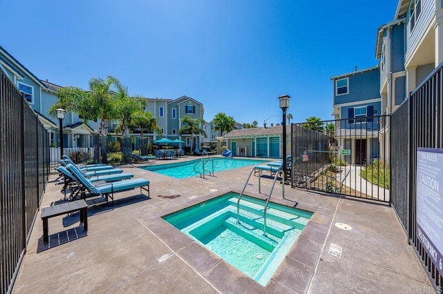 community pool with a residential view, a community hot tub, a patio, and fence