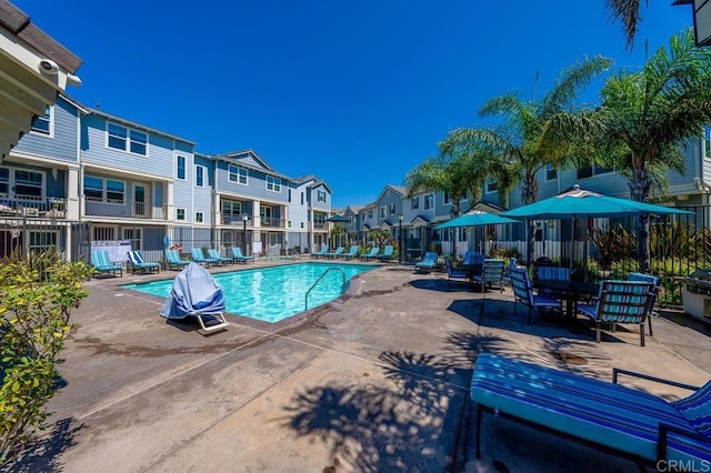 pool with a residential view, a patio, and fence