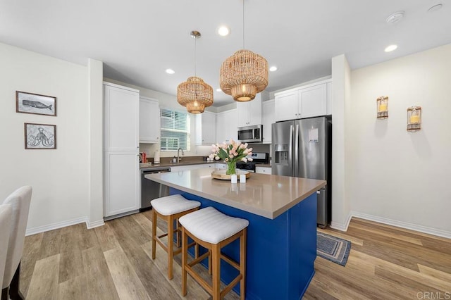 kitchen with a sink, stainless steel appliances, a kitchen bar, and white cabinets