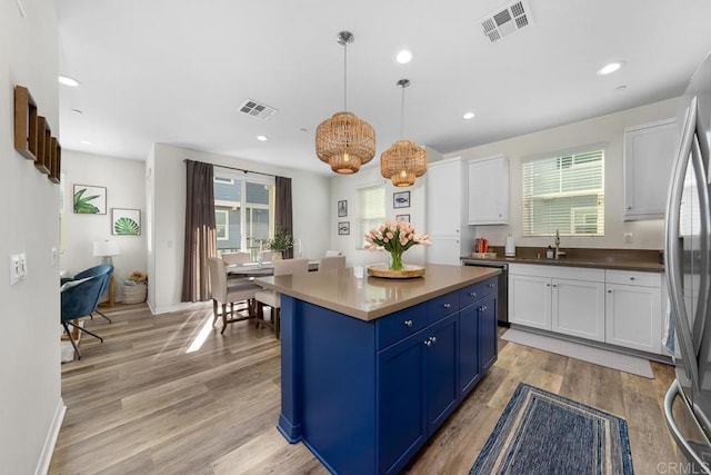 kitchen featuring visible vents, blue cabinetry, a sink, appliances with stainless steel finishes, and white cabinets