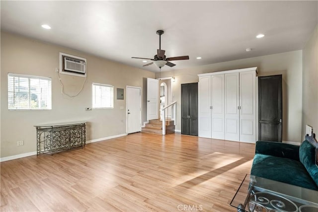 living room with baseboards, a ceiling fan, light wood-type flooring, and a wall mounted AC