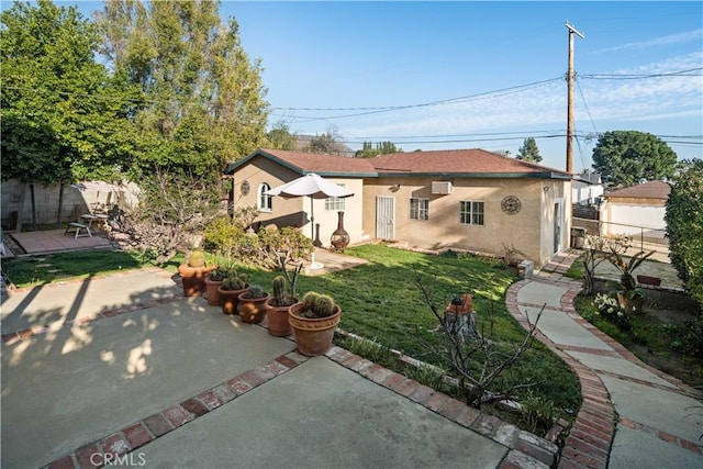 exterior space with a patio, a lawn, fence, and stucco siding