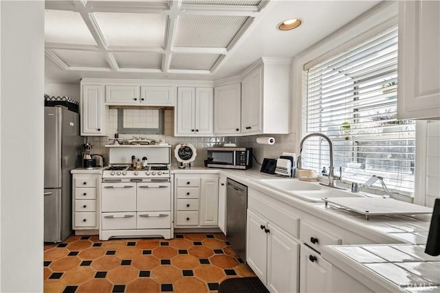 kitchen featuring a sink, tasteful backsplash, coffered ceiling, stainless steel appliances, and white cabinets