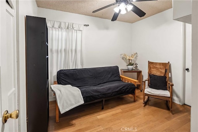 sitting room featuring a textured ceiling, light wood-style floors, and ceiling fan