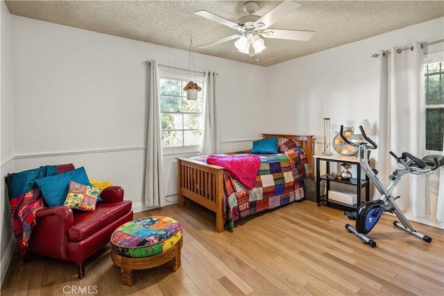 bedroom with a textured ceiling, wood finished floors, and a ceiling fan