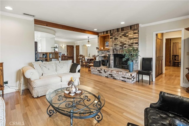 living area with visible vents, ornamental molding, and light wood-style flooring