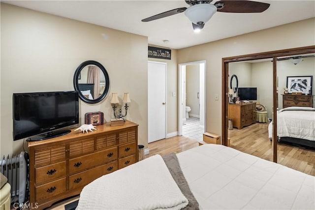 bedroom with connected bathroom, baseboards, ceiling fan, radiator heating unit, and light wood-style flooring