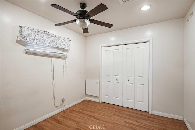 unfurnished bedroom with light wood finished floors, ceiling fan, a closet, and baseboards