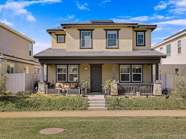 view of front of home featuring covered porch, solar panels, and fence