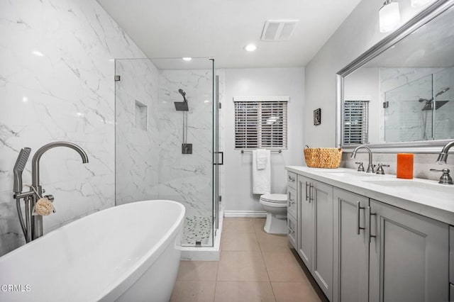 bathroom featuring a marble finish shower, double vanity, a soaking tub, a sink, and toilet