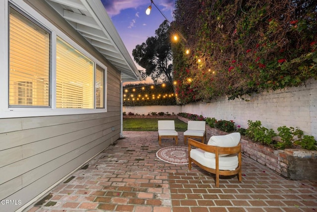 patio terrace at dusk featuring a fenced backyard