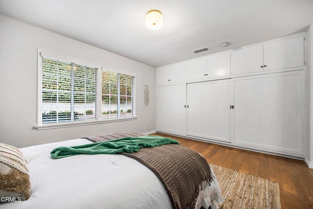 bedroom featuring wood finished floors, visible vents, and a closet