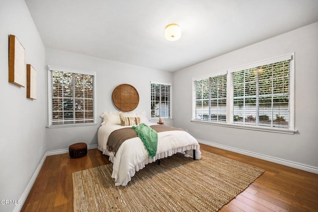 bedroom with multiple windows, baseboards, and wood-type flooring