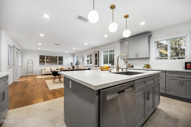 kitchen featuring visible vents, dishwasher, light countertops, gray cabinets, and a sink