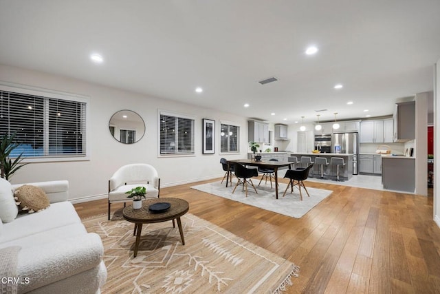 living room with recessed lighting, visible vents, and light wood finished floors