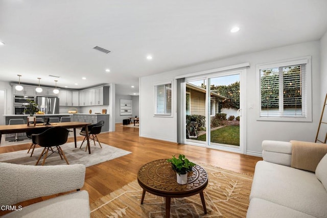 living area featuring recessed lighting, light wood-style floors, visible vents, and baseboards