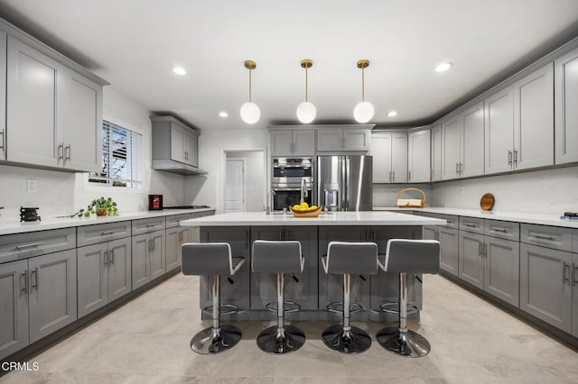 kitchen with gray cabinets, stainless steel appliances, and a kitchen bar