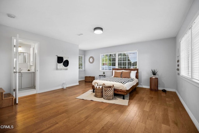 bedroom featuring baseboards, multiple windows, and wood finished floors