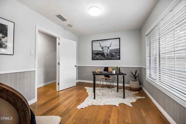 office with visible vents, wood finished floors, and a wainscoted wall