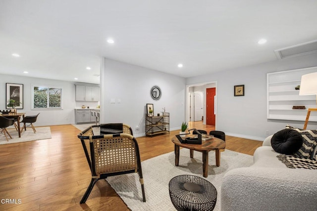 living area featuring recessed lighting, baseboards, and light wood-style flooring