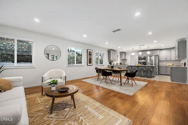 living room featuring recessed lighting, visible vents, baseboards, and light wood finished floors