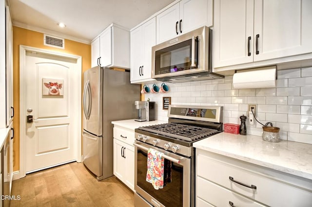 kitchen with visible vents, light wood-style flooring, white cabinets, appliances with stainless steel finishes, and tasteful backsplash