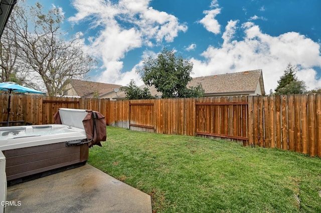 view of yard with a patio area, a fenced backyard, and a hot tub