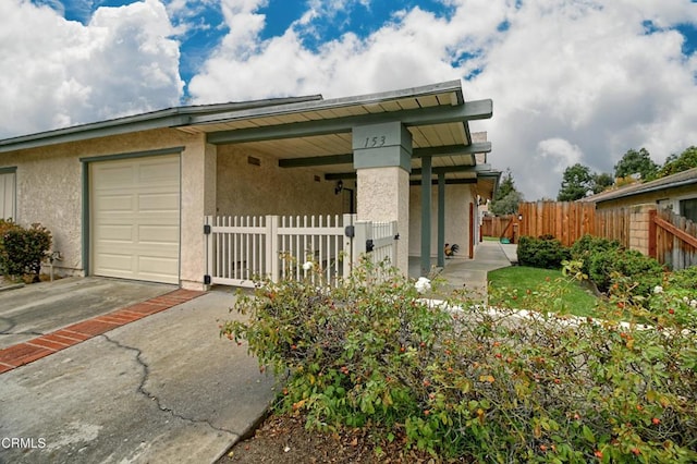 view of front of house with an attached garage, fence, driveway, and stucco siding