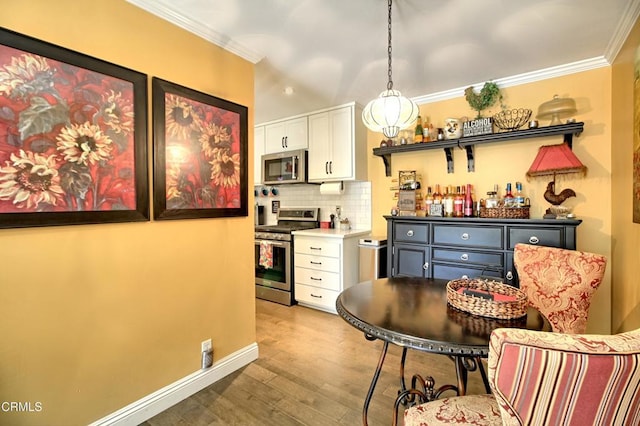 kitchen featuring tasteful backsplash, white cabinetry, stainless steel appliances, and ornamental molding