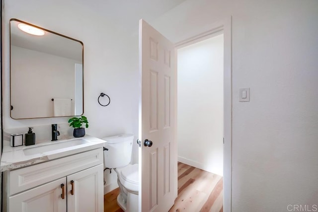 bathroom with toilet, vanity, and wood finished floors