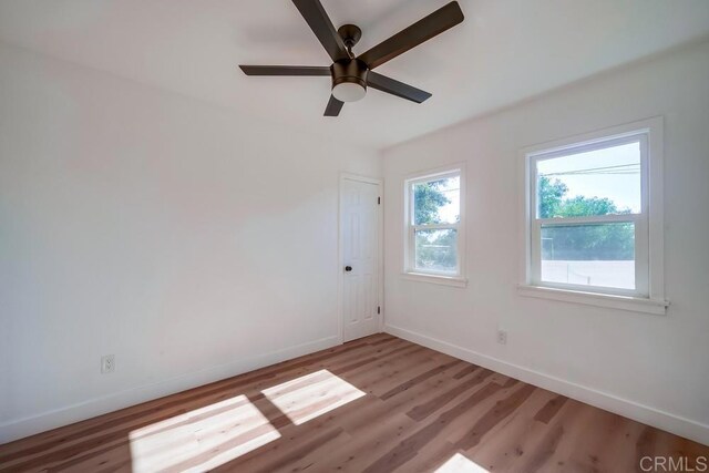 spare room featuring light wood finished floors, ceiling fan, and baseboards