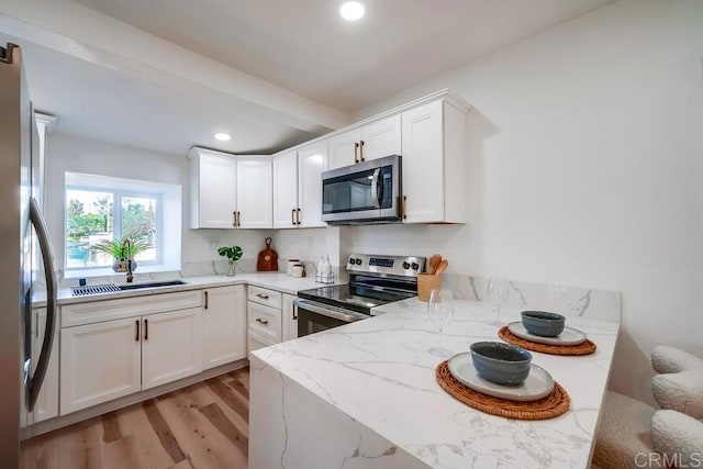 kitchen featuring light stone counters, recessed lighting, light wood-style floors, appliances with stainless steel finishes, and white cabinetry