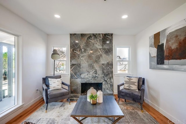 living area featuring recessed lighting, a fireplace, baseboards, and wood finished floors