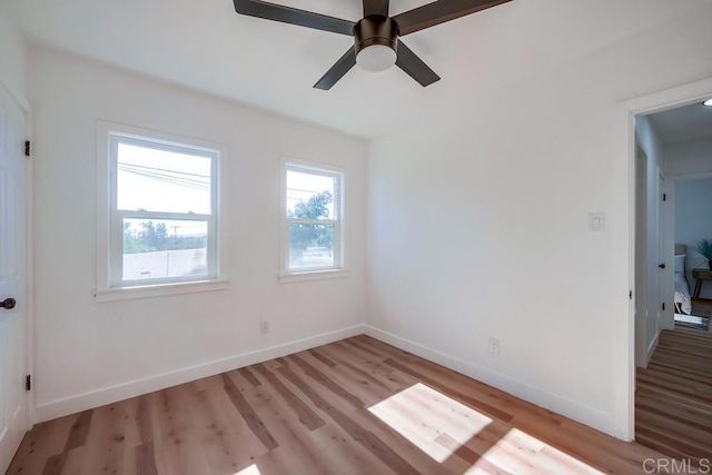 unfurnished room with light wood-style flooring, a ceiling fan, and baseboards