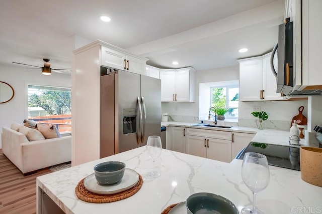 kitchen featuring recessed lighting, appliances with stainless steel finishes, light stone countertops, and a sink