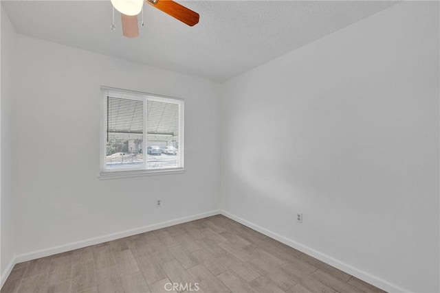 spare room featuring baseboards, a textured ceiling, light wood-style flooring, and a ceiling fan