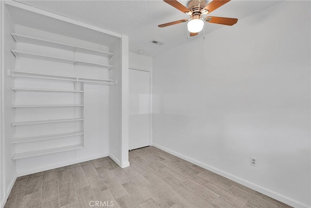 unfurnished bedroom featuring visible vents, baseboards, wood finished floors, a closet, and a textured ceiling