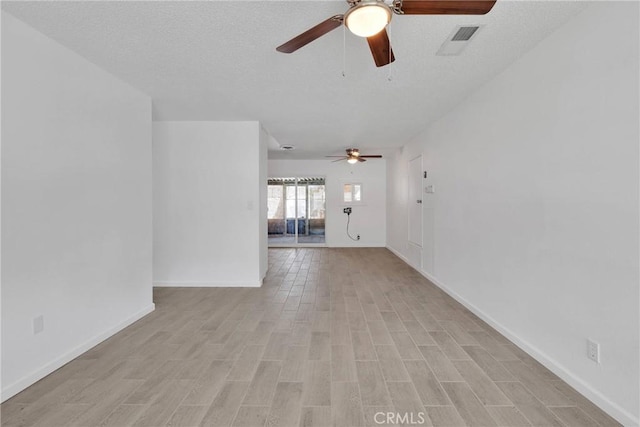 unfurnished room with baseboards, visible vents, light wood finished floors, ceiling fan, and a textured ceiling