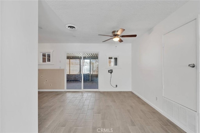 unfurnished room with visible vents, a textured ceiling, a ceiling fan, and wood finished floors