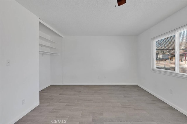 empty room featuring light wood-style flooring, a textured ceiling, and baseboards