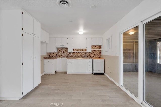 kitchen featuring decorative backsplash, dishwasher, white cabinets, and visible vents