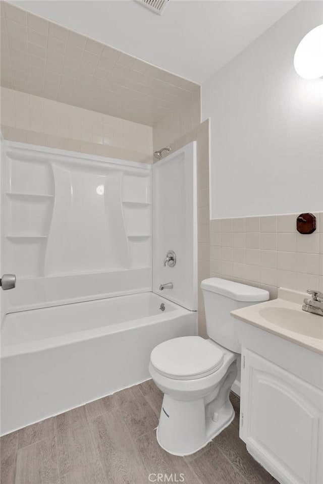 bathroom with bathing tub / shower combination, tile walls, wood finished floors, and vanity