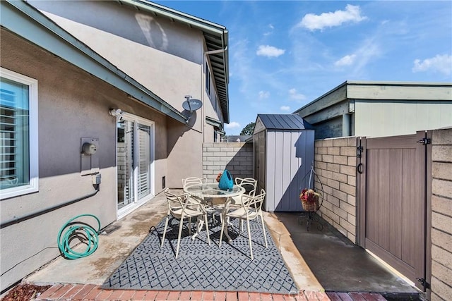 view of patio / terrace with outdoor dining area, fence, an outdoor structure, and a shed