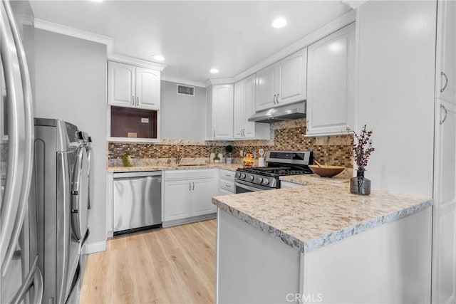 kitchen featuring visible vents, a peninsula, a sink, stainless steel appliances, and under cabinet range hood